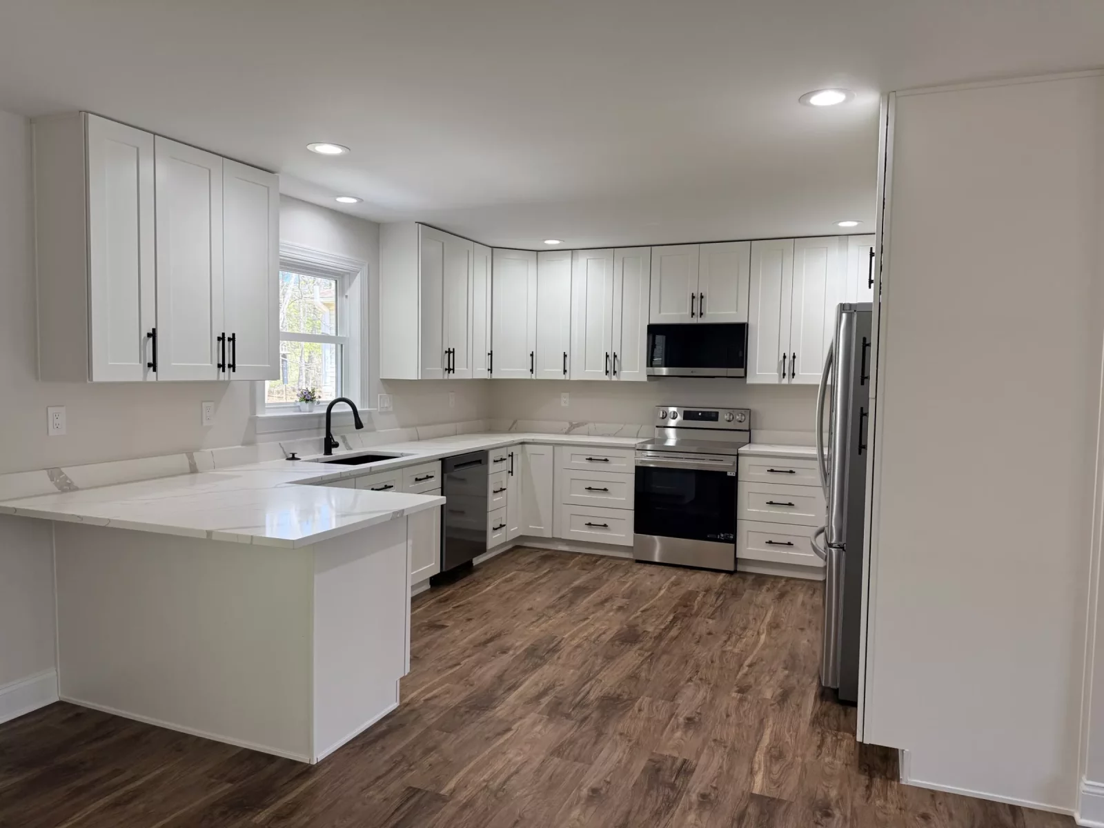 Remodeled open-concept kitchen in Locust Grove, VA with white shaker cabinets, quartz peninsula, and stainless steel appliances