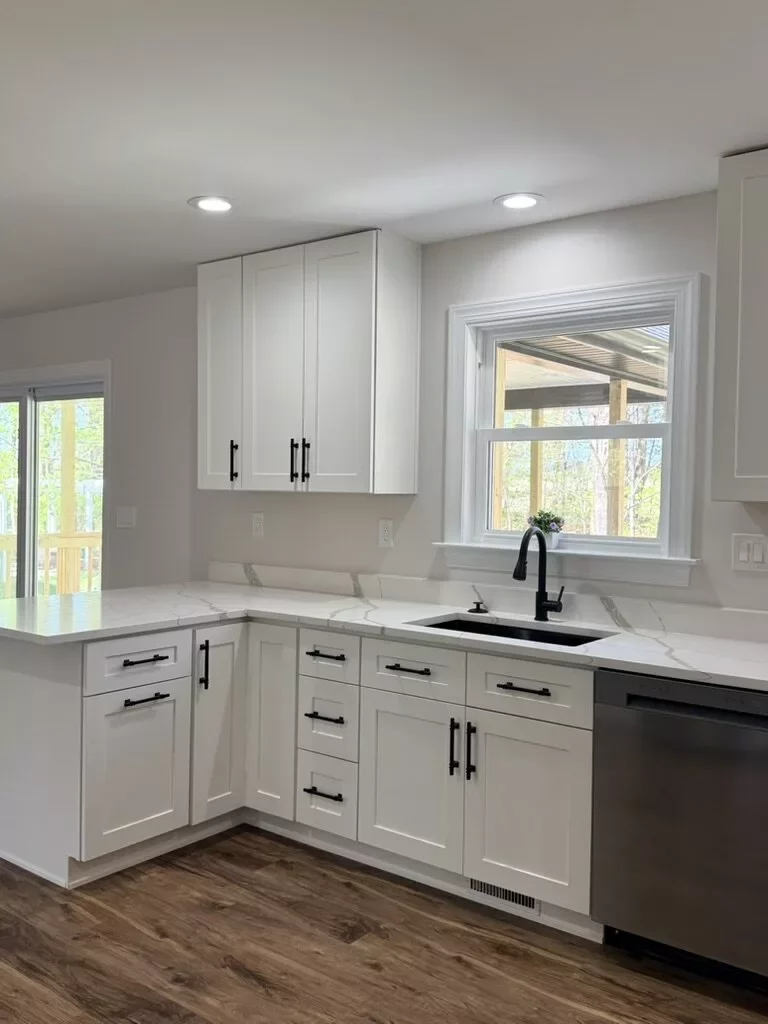 Bright remodeled kitchen with white cabinetry, matte-black hardware, quartz countertops, and two windows over the sink