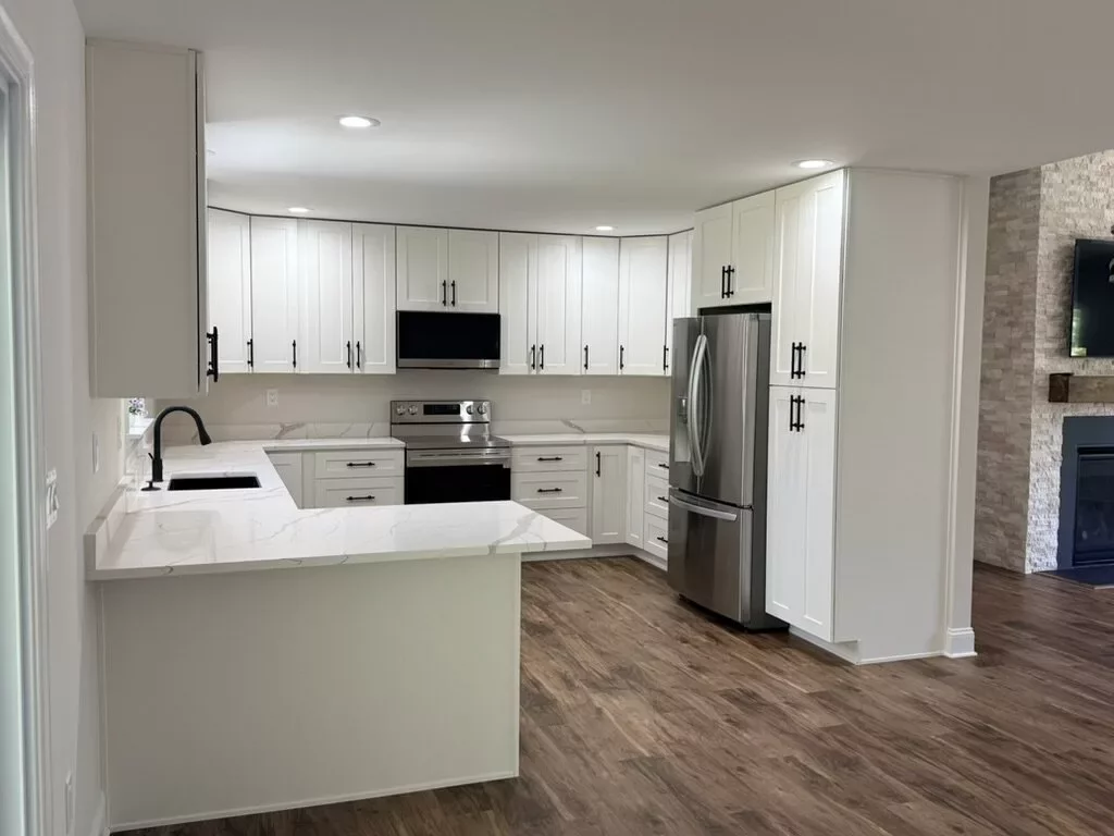 Modern farmhouse kitchen remodel with white cabinets, quartz peninsula, and black-and-stainless appliance package