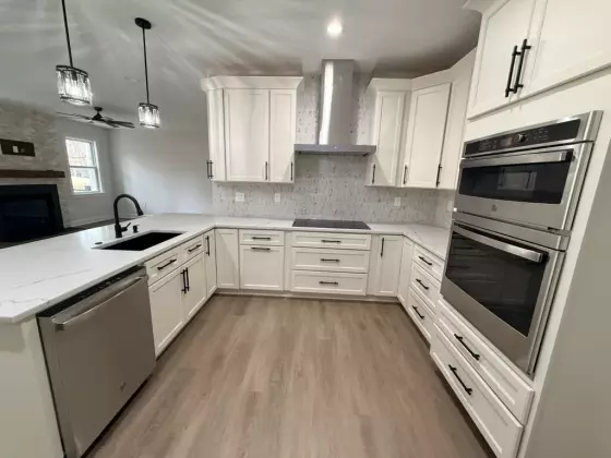White shaker kitchen with a tile backsplash, built-in cooktop, double wall ovens, and quartz countertops