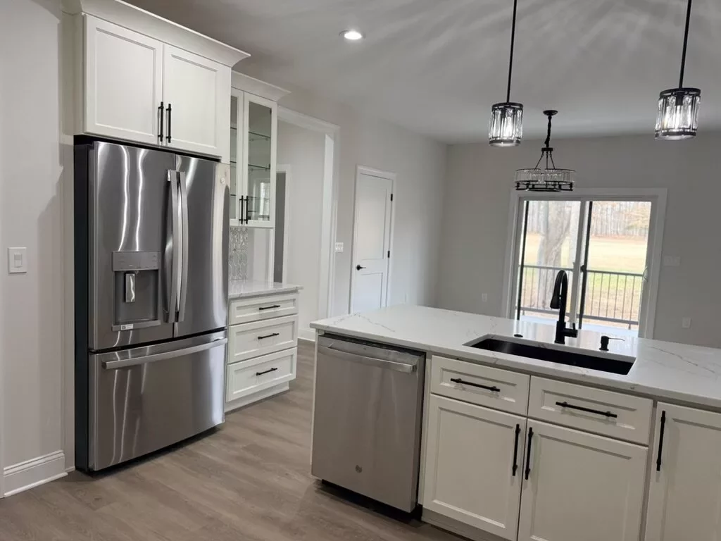 Open-concept kitchen with white cabinets and quartz island opening into the living and dining area