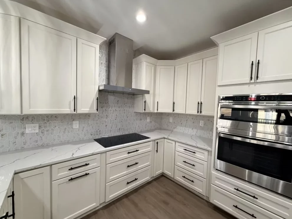U-shaped custom kitchen with white cabinetry, range hood, quartz counters, and wood-look flooring