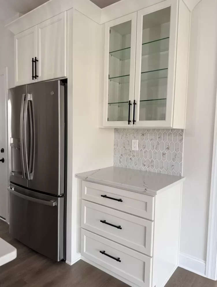 Stainless steel French-door refrigerator framed by white cabinetry with glass-front upper cabinets