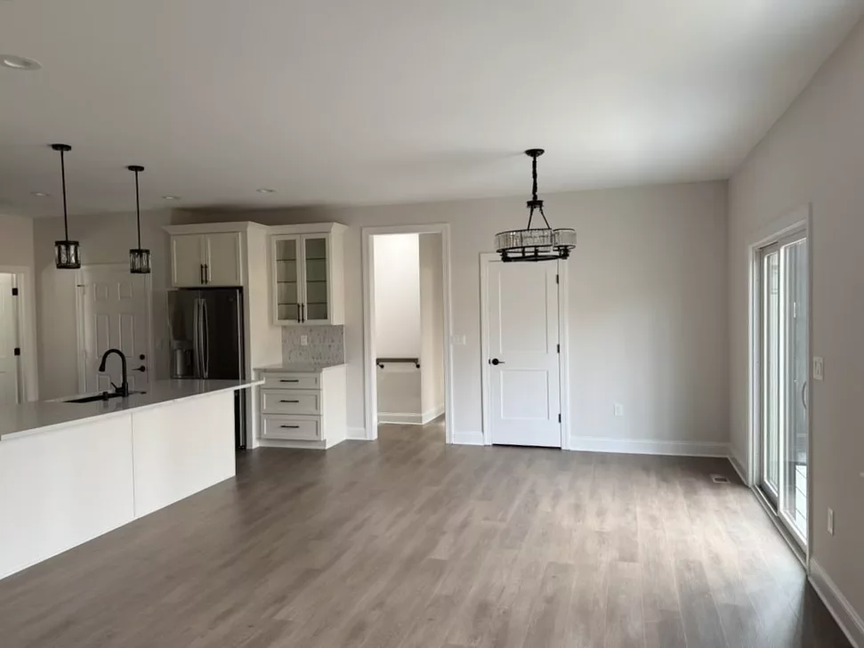 Custom kitchen corner with a stainless range hood, tile backsplash, double ovens, and white shaker cabinets