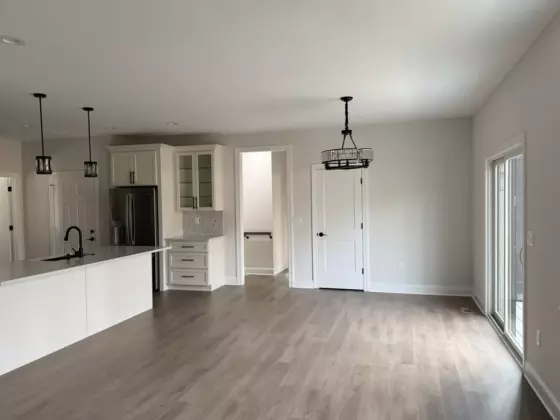 Custom kitchen corner with a stainless range hood, tile backsplash, double ovens, and white shaker cabinets