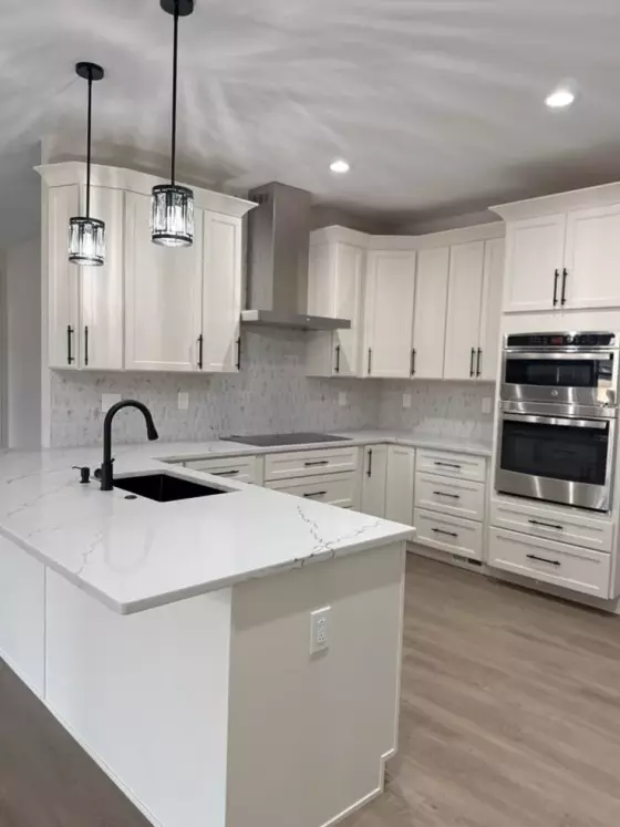 Kitchen island with a waterfall-edge quartz countertop, black faucet, and undermount sink beside stainless steel appliances