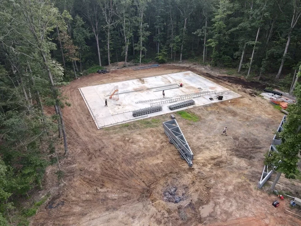 Aerial view of a completed concrete foundation slab on a wooded construction site