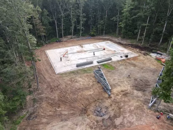 Aerial view of a completed concrete foundation slab on a wooded construction site