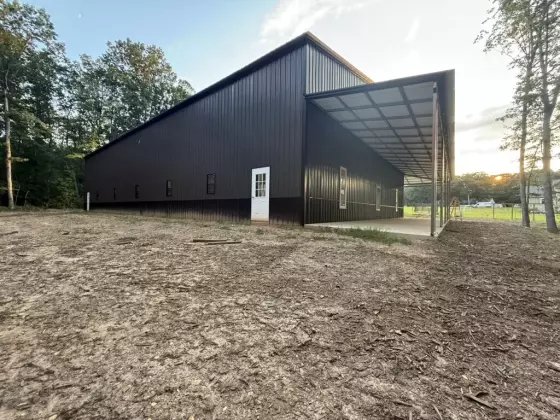 Exterior of the completed dark metal building with vertical steel siding, covered overhang, and entry door