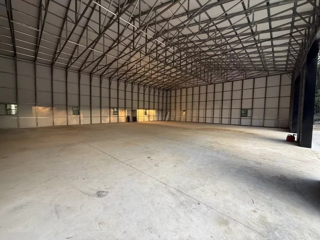 Open interior of the metal building with exposed steel framing, concrete floor, and natural light
