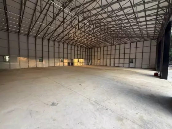 Open interior of the metal building with exposed steel framing, concrete floor, and natural light