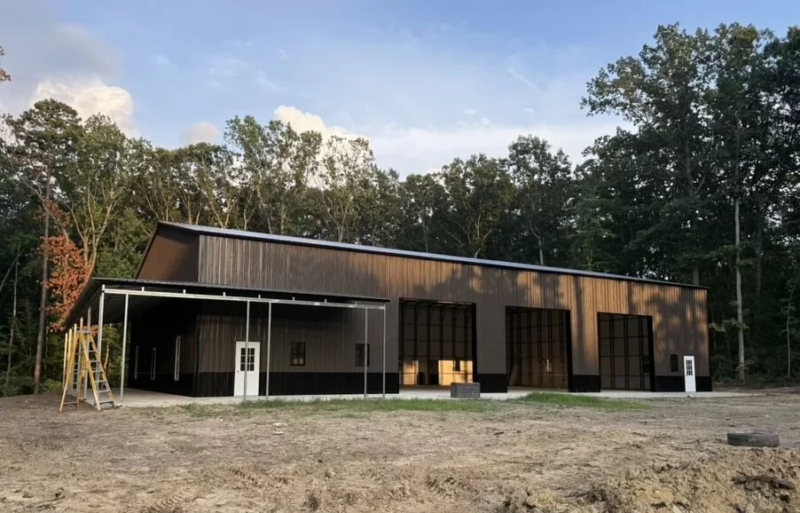 Completed custom metal building in Locust Grove, VA with dark steel siding, a covered front bay, and a sloped roof on a cleared lot