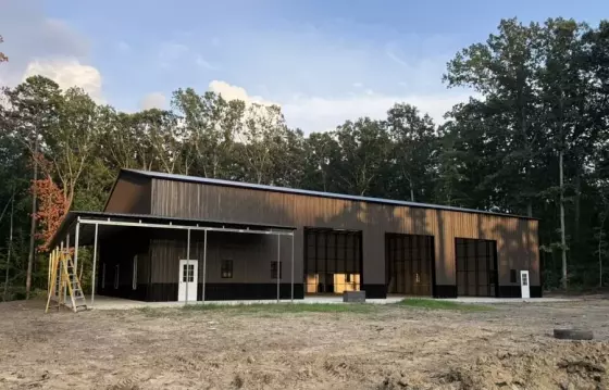 Completed custom metal building in Locust Grove, VA with dark steel siding, a covered front bay, and a sloped roof on a cleared lot